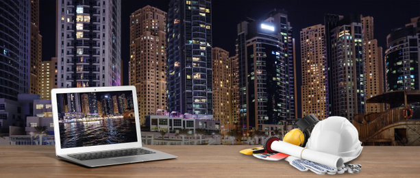 Laptop with engineer equipment on table and night cityscape. Banner design