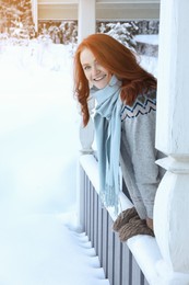 Beautiful young woman looking out from wooden gazebo on snowy day outdoors. Winter vacation