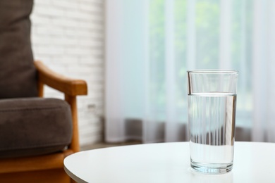 Photo of Glass of water on table in room, space for text. Refreshing drink