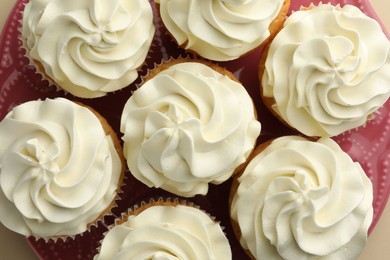 Photo of Tasty vanilla cupcakes with cream on beige background, flat lay