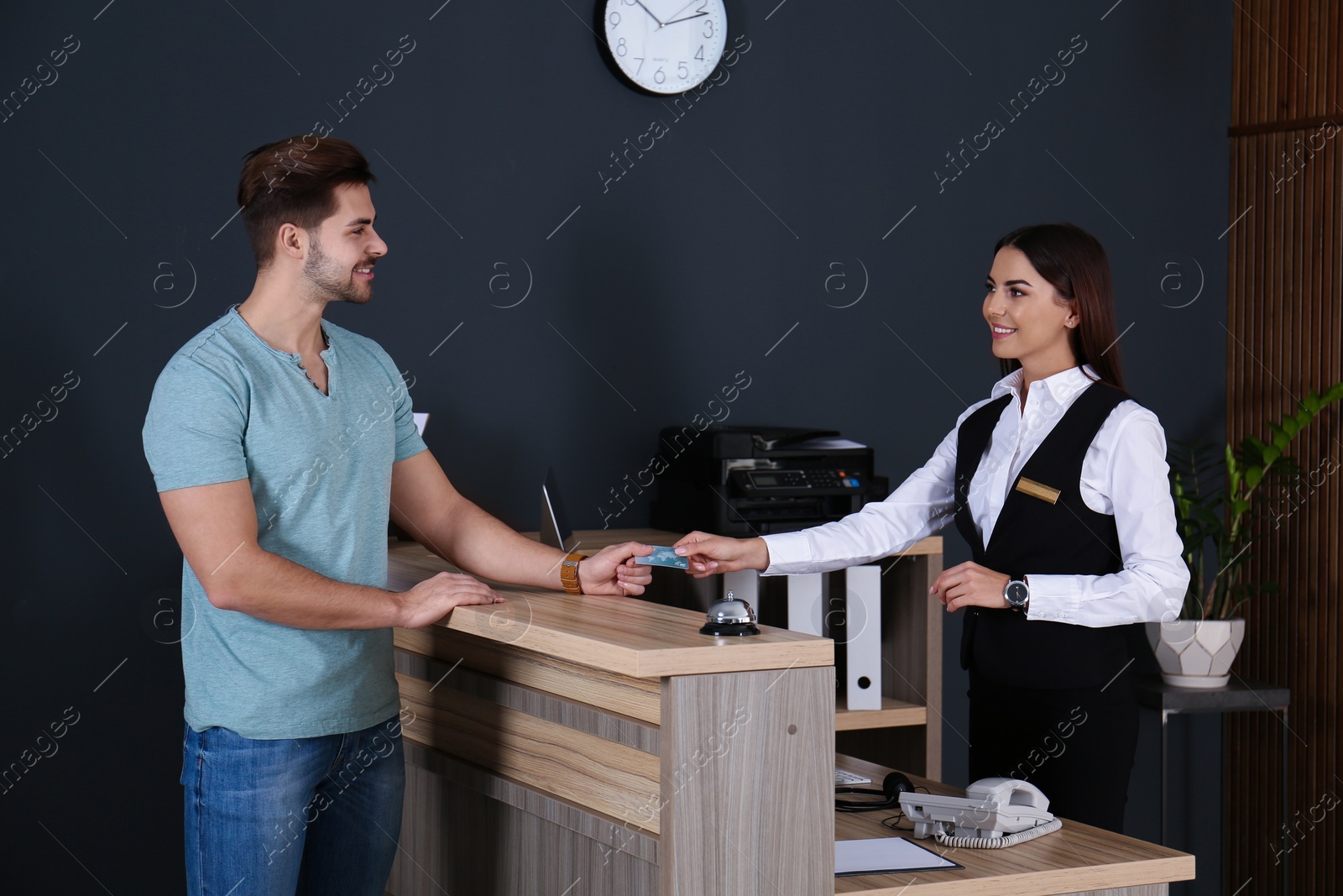 Photo of Client paying with credit card for service to receptionist at desk in lobby