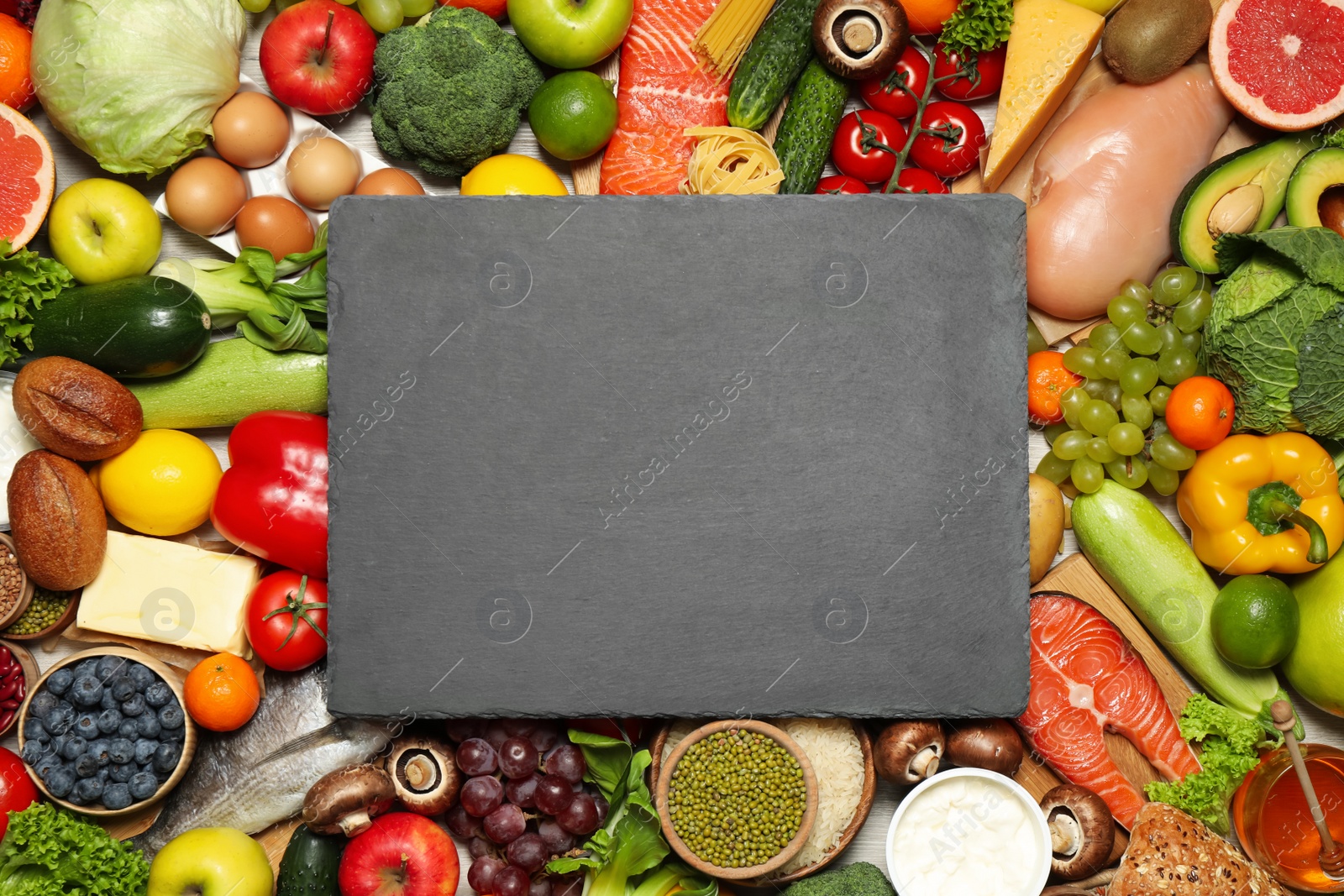 Photo of Slate board on pile of different food products, top view with space for text. Healthy balanced diet