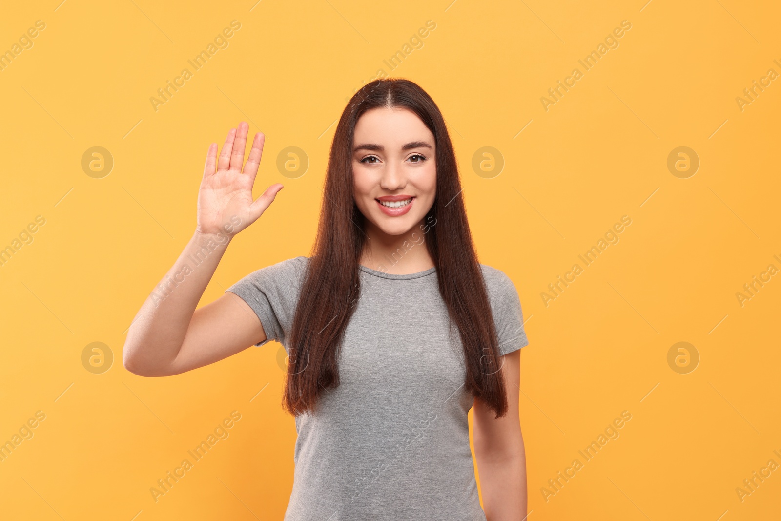 Photo of Happy woman giving high five on orange background