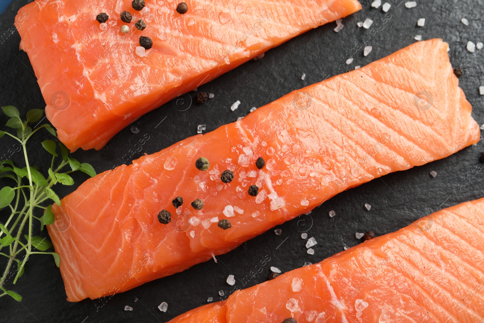 Photo of Fresh raw salmon and ingredients for marinade on black table, closeup