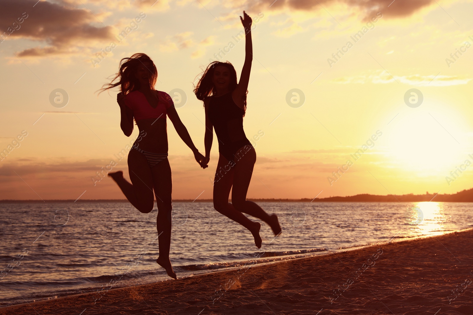 Photo of Young woman in bikini with girlfriend on beach. Lovely couple