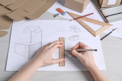 Photo of Woman creating packaging design at light wooden table, closeup