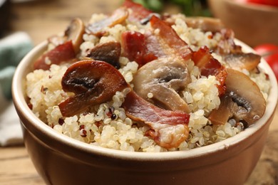 Photo of Tasty quinoa porridge with fried bacon and mushrooms in bowl, closeup