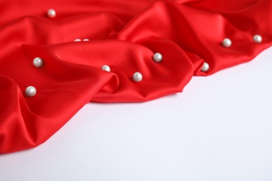 Photo of Texture of delicate red silk with pearls on white background