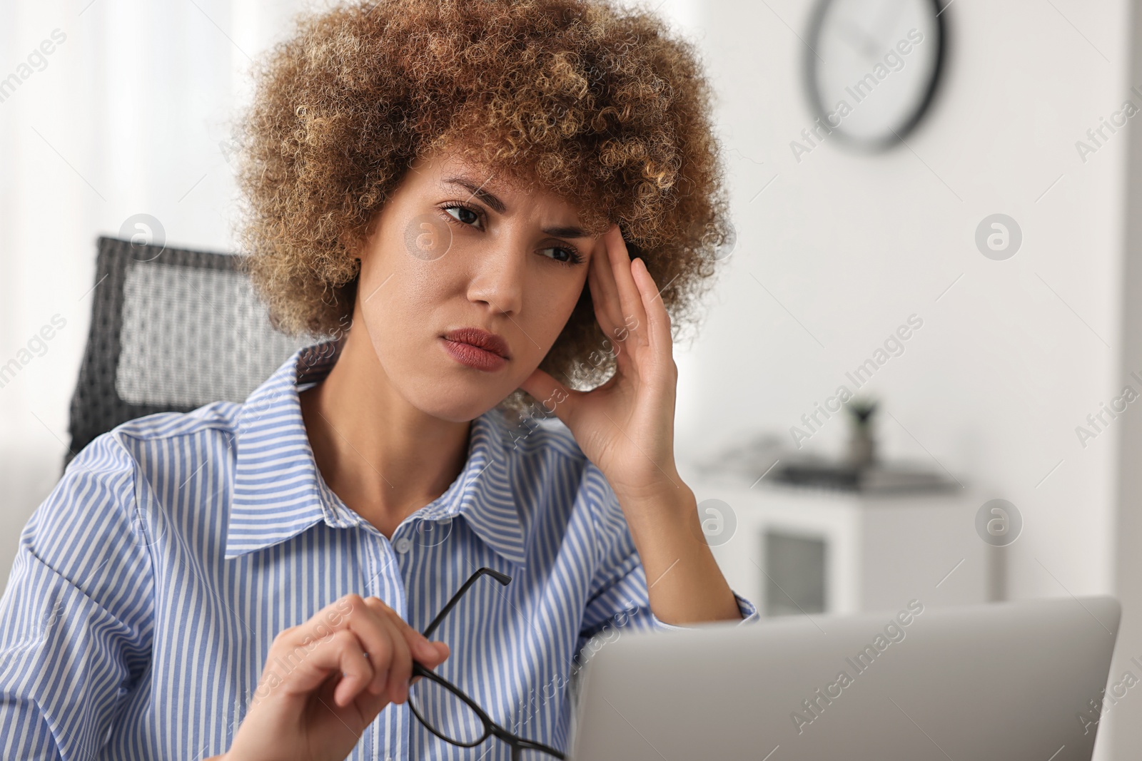 Photo of Woman suffering from headache at workplace in office