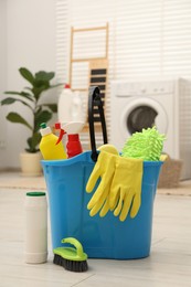 Different cleaning products and bucket on floor indoors