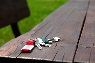 Photo of Keys forgotten on wooden bench outdoors. Lost and found