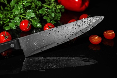 Chef's knife and products on black background