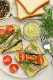 Photo of Delicious sandwiches with sprats, tomatoes, dill and avocado puree served on white wooden table, flat lay