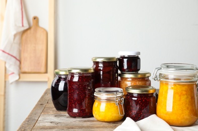 Photo of Jars with different jams on wooden table