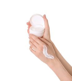 Young woman applying cream onto her hands on white background, closeup