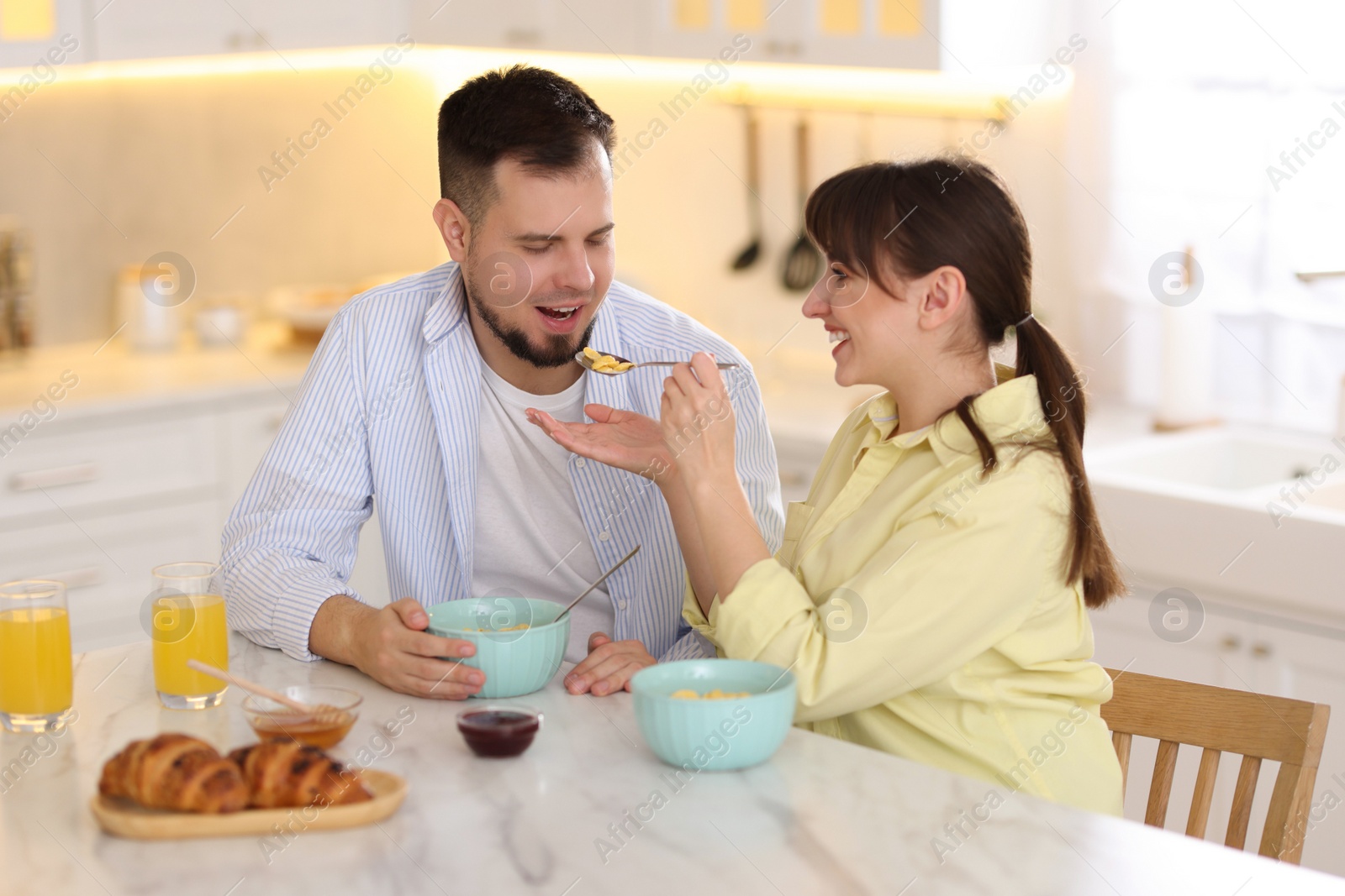 Photo of Tasty breakfast. Happy wife feeding her husband at home