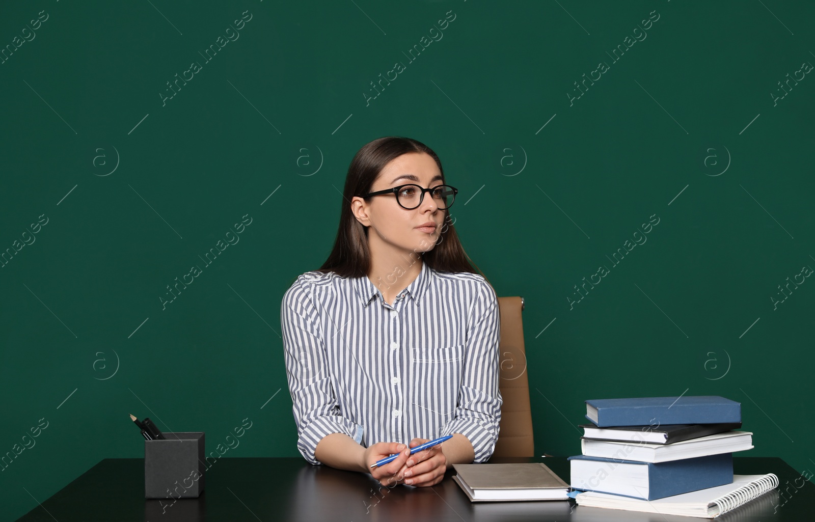 Photo of Portrait of young teacher at table against green background