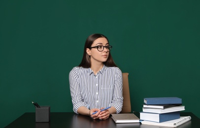 Photo of Portrait of young teacher at table against green background