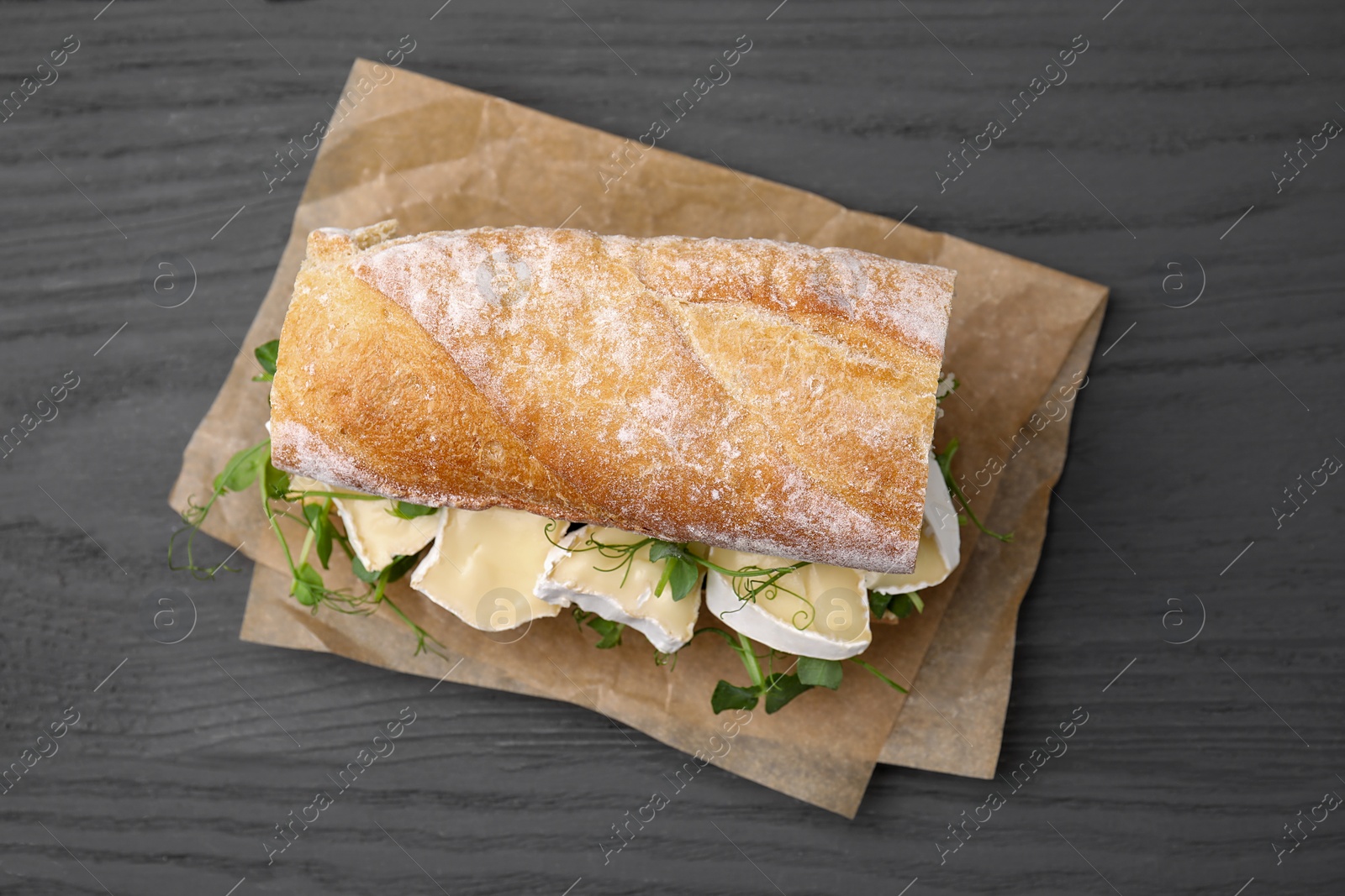 Photo of Tasty sandwich with brie cheese on grey wooden table, top view