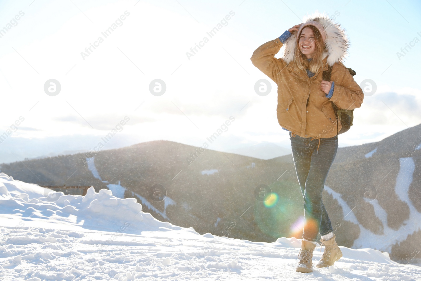 Photo of Happy young woman with backpack spending winter vacation in mountains. Space for text