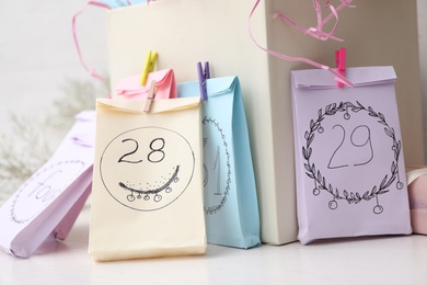 Photo of Colorful paper bags on white table, closeup. New Year advent calendar