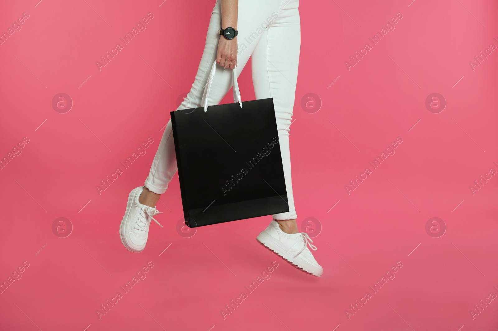 Photo of Woman jumping with paper shopping bag on color background. Mock up for design