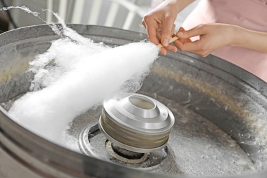 Woman making cotton candy using modern machine indoors, closeup