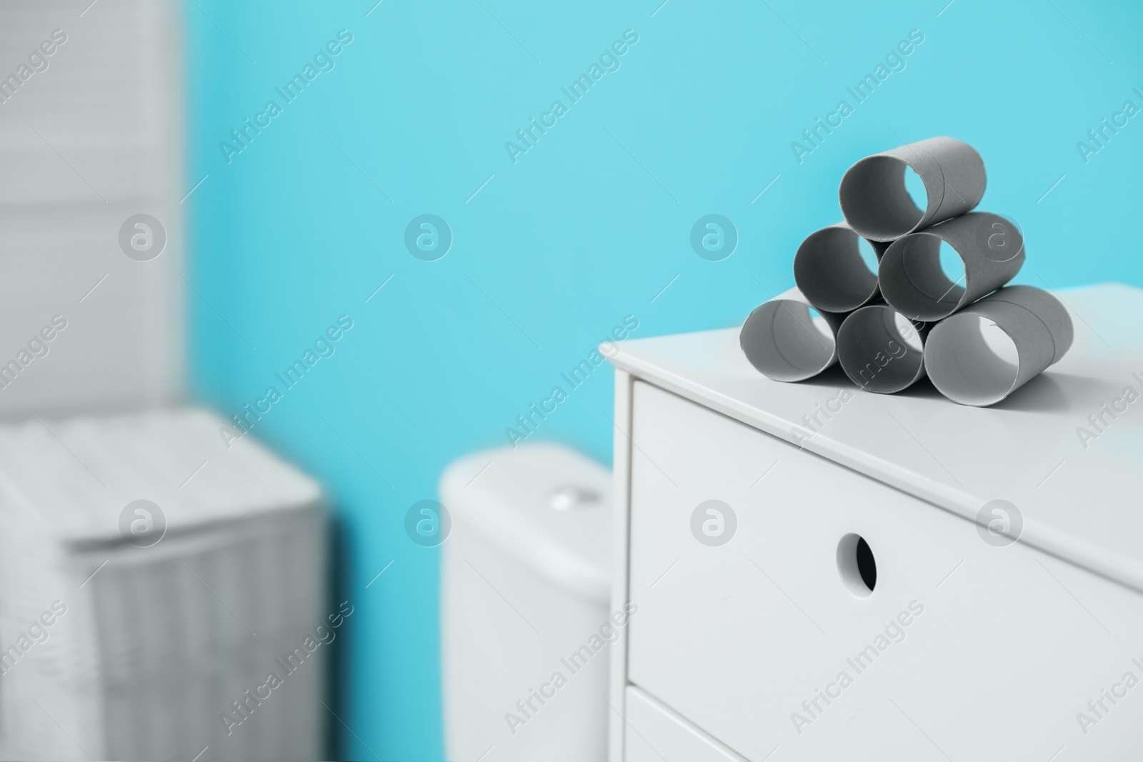 Photo of Empty toilet paper rolls on cabinet in bathroom. Space for text