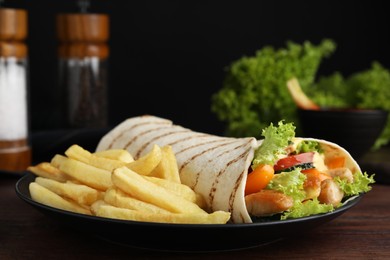 Delicious chicken shawarma and French fries on wooden table