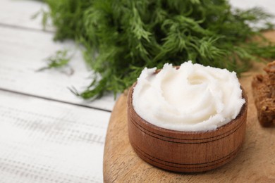 Delicious pork lard in bowl on wooden board, closeup. Space for text