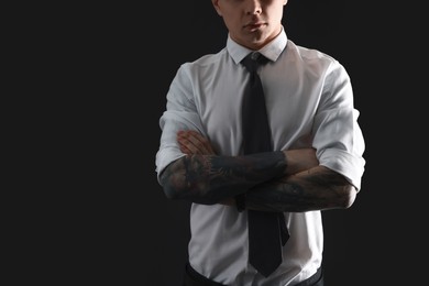 Young man with tattoos on black background, closeup. Space for text