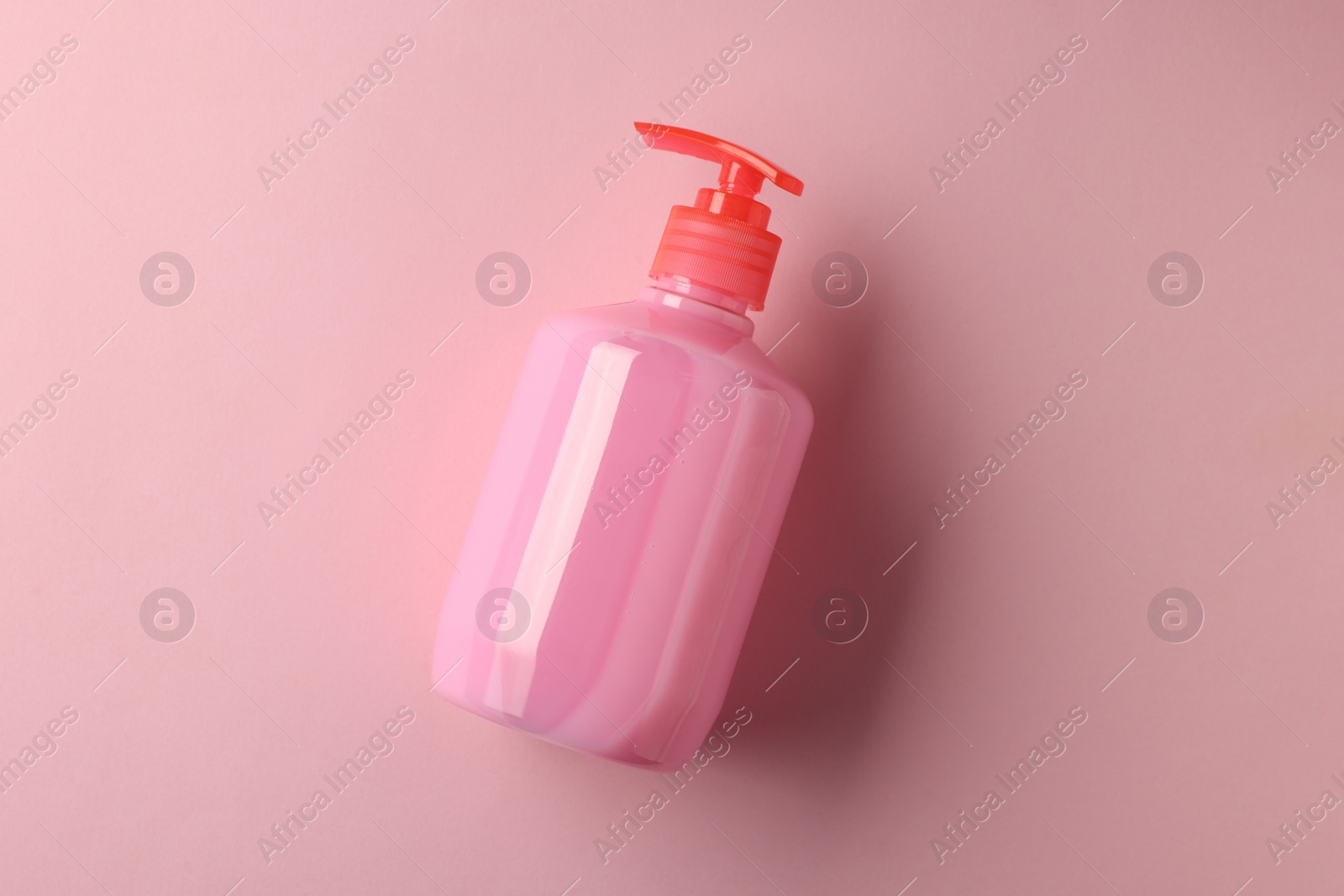 Photo of Bottle of liquid soap on pink background, top view