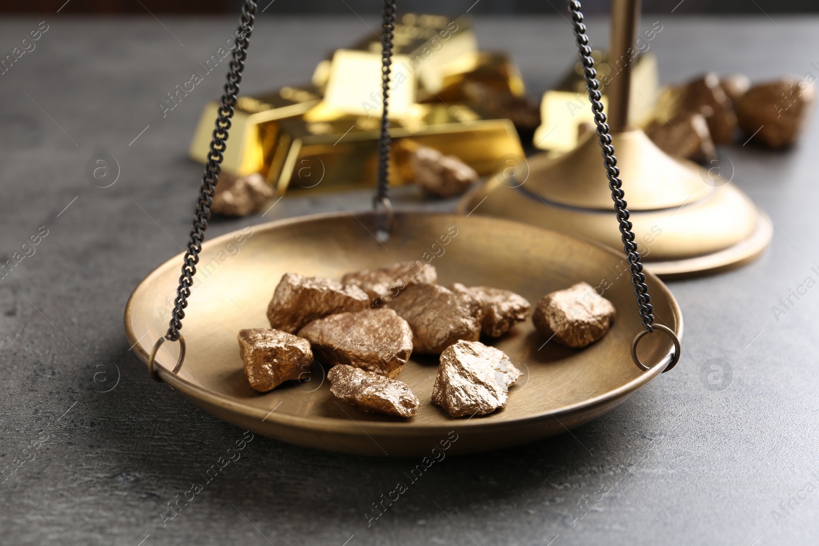 Photo of Scale pan with gold lumps on grey table, closeup