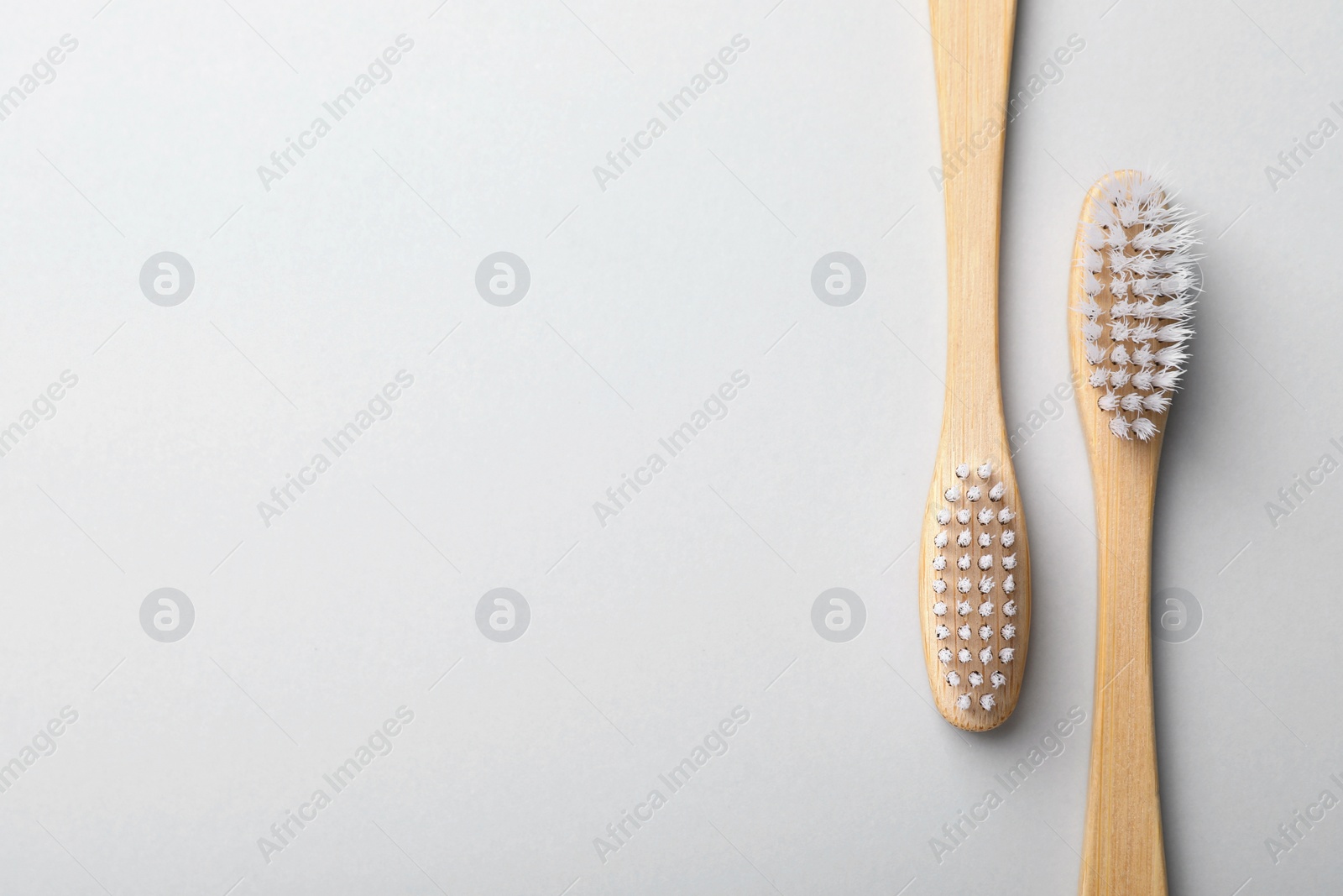 Photo of Bamboo toothbrushes on light background, flat lay. Space for text