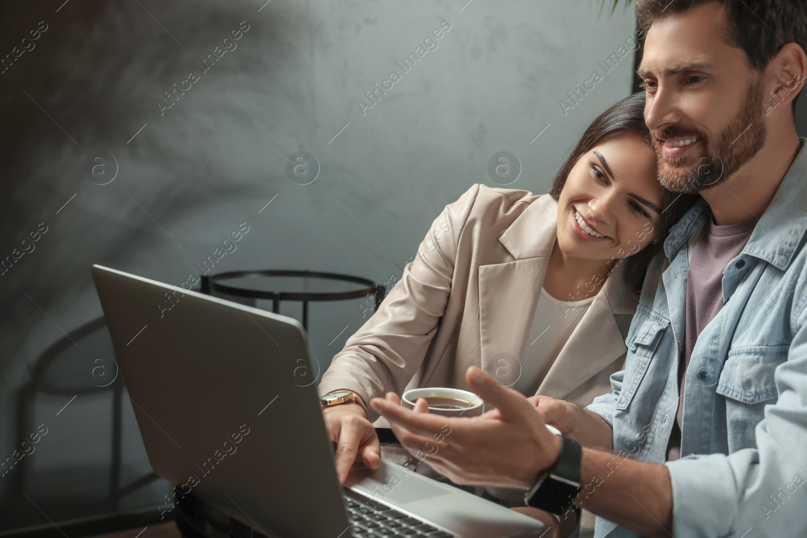 Photo of Couple with coffee and laptop spending time together in cafe