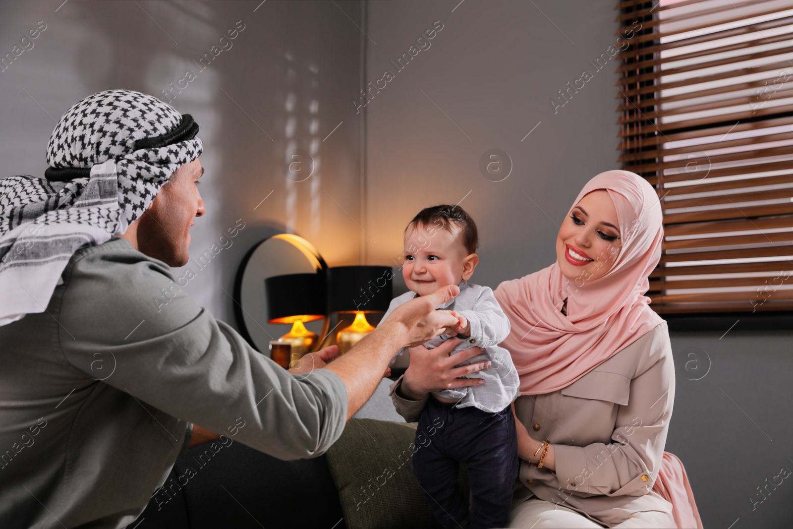 Photo of Happy Muslim family with little son in living room