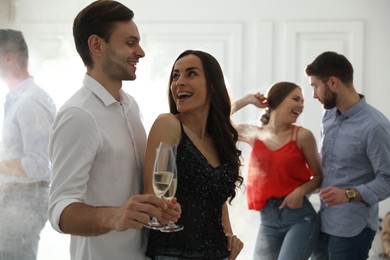 Photo of Lovely young couple with glasses of champagne at dancing party
