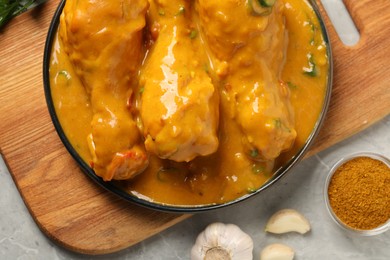 Tasty chicken curry and ingredients on grey textured table, flat lay