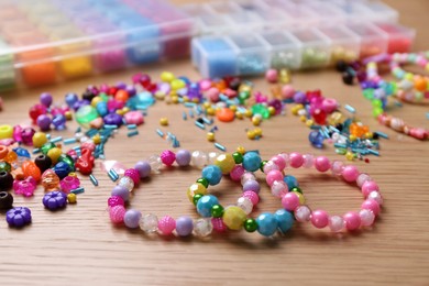 Photo of Beautiful handmade beaded bracelets and supplies on wooden table