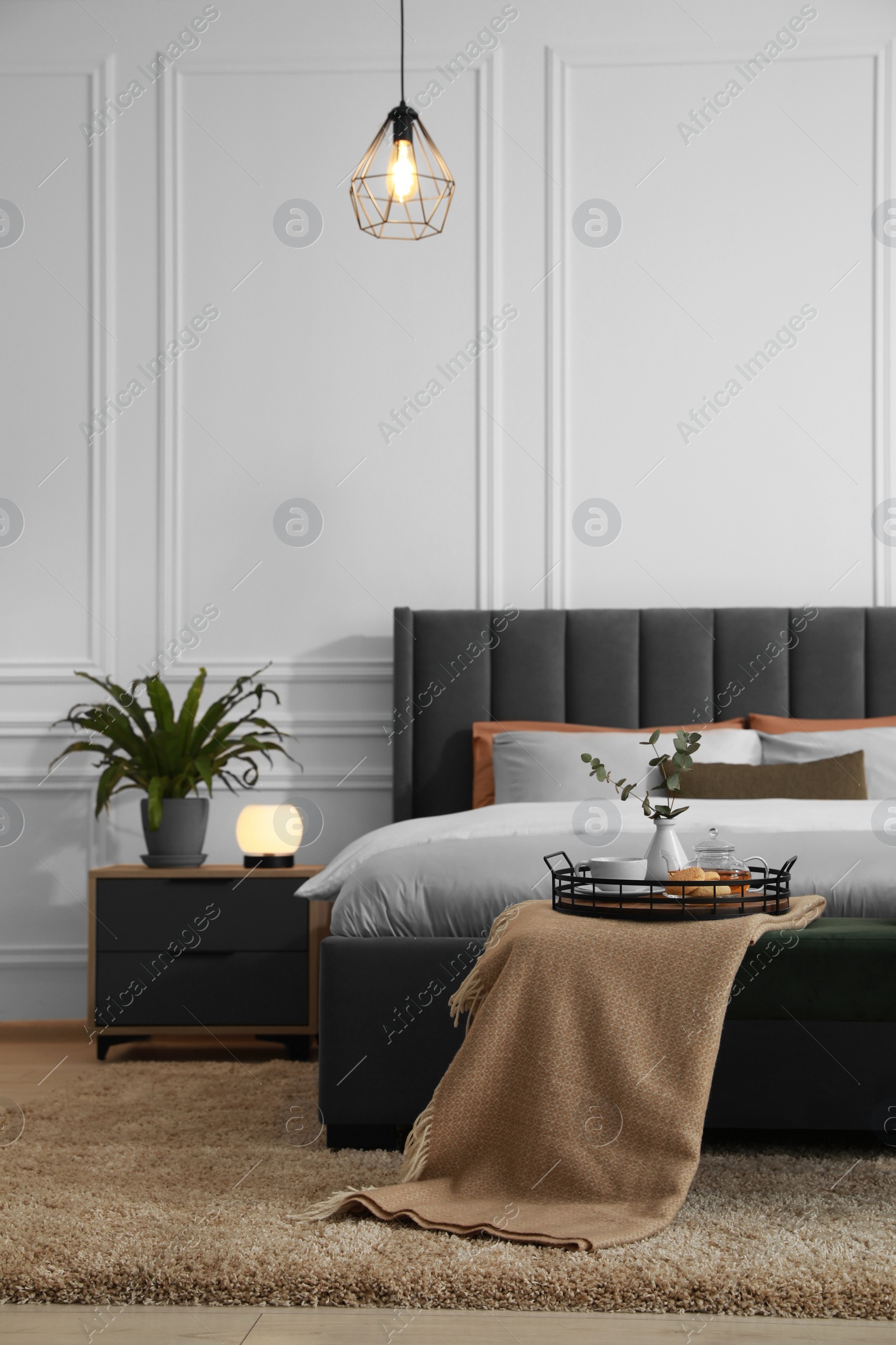 Photo of Stylish bedroom interior with large comfortable bed and ottoman