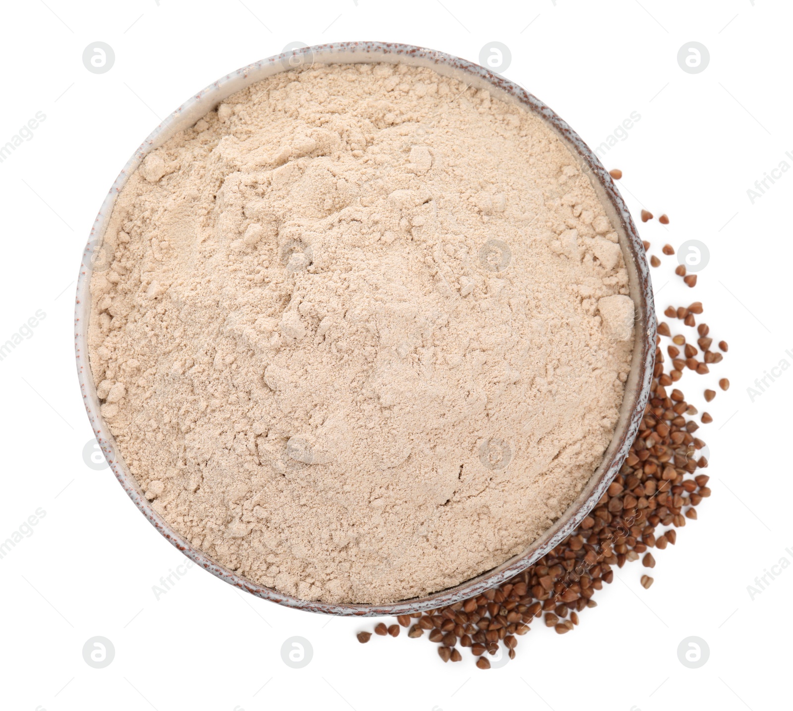 Photo of Bowl with buckwheat flour and grains on white background, top view