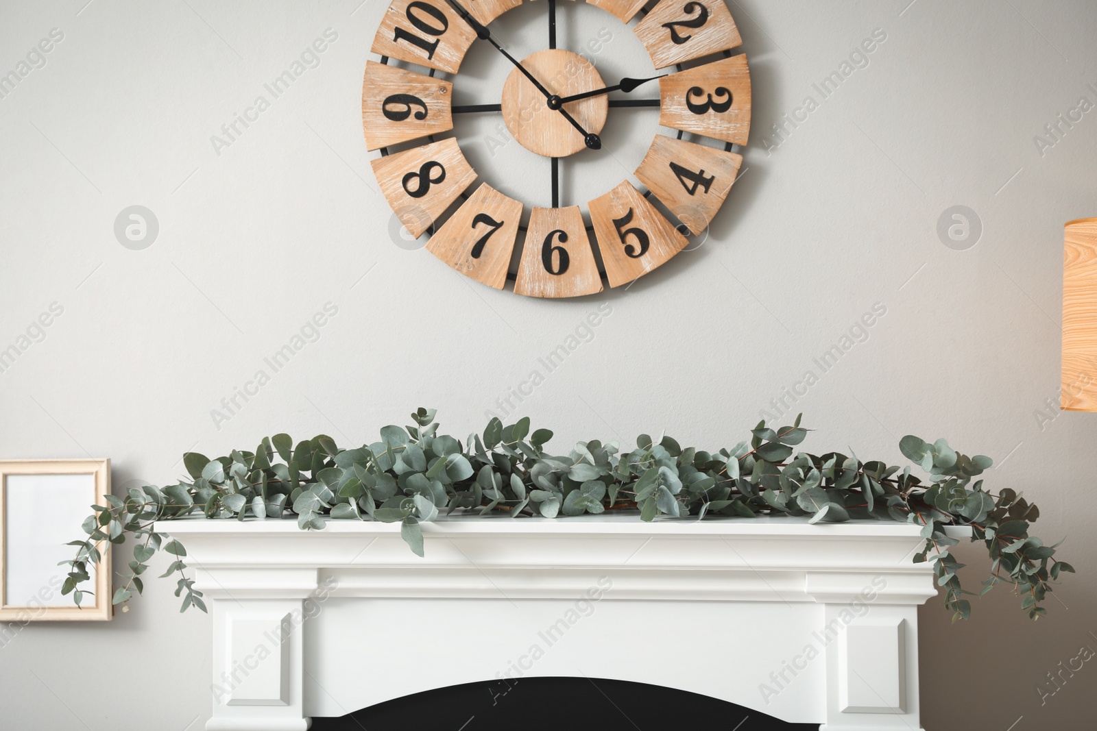 Photo of Beautiful garland with eucalyptus branches on mantelpiece in room