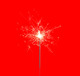 Image of Beautiful sparkler burning on red background. Party decor