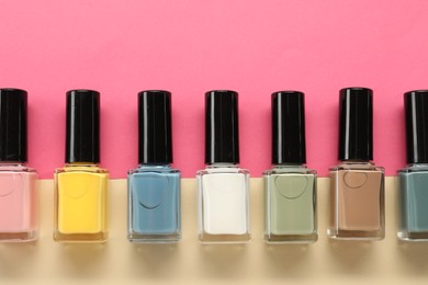 Photo of Beautiful nail polishes in bottles on color background, flat lay