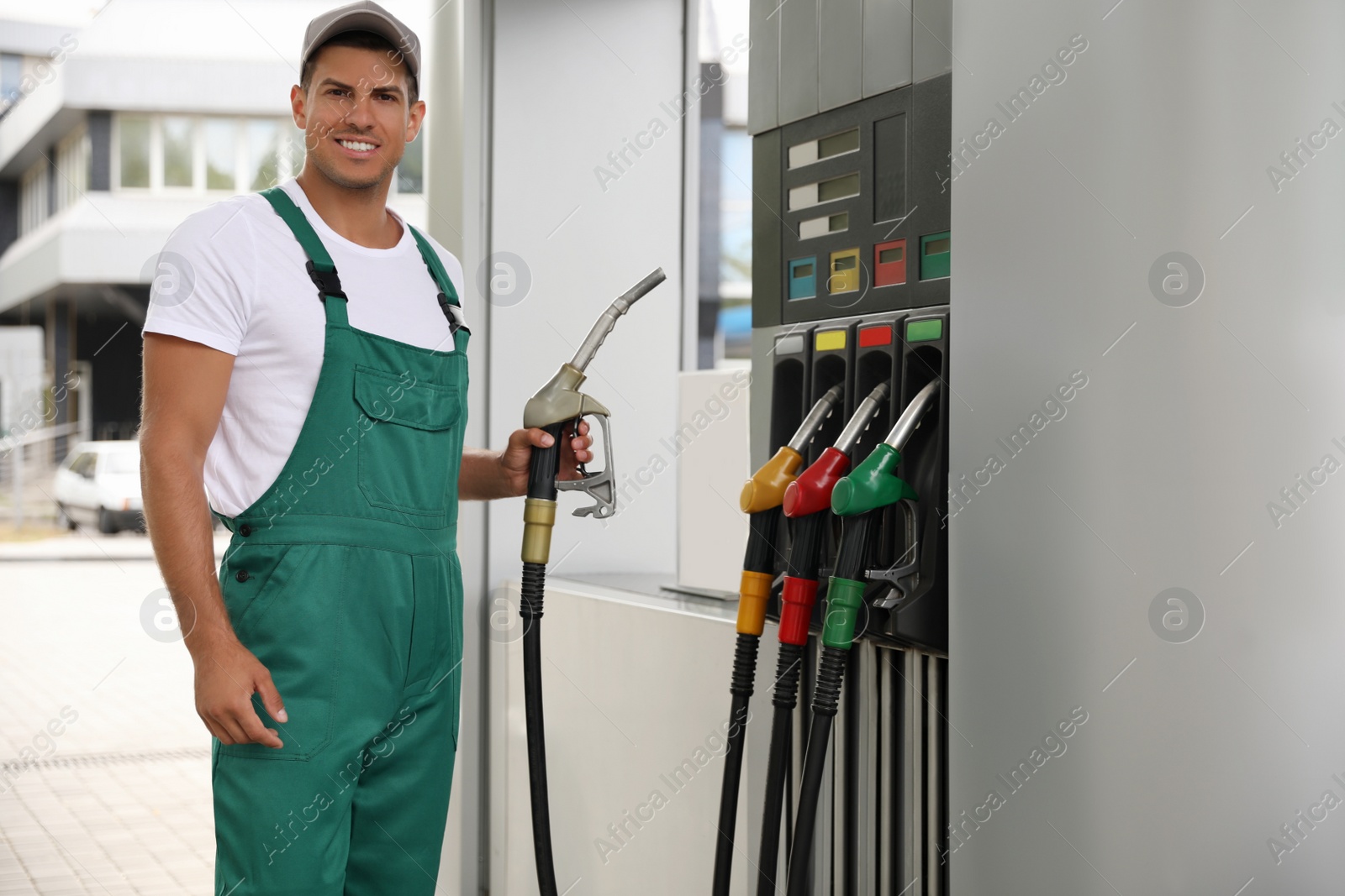 Photo of Worker taking fuel pump nozzle at modern gas station