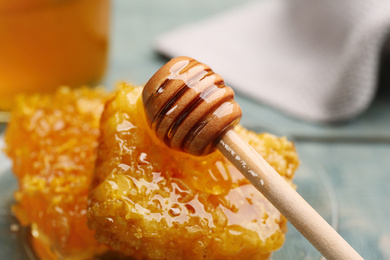 Photo of Tasty honey combs and wooden dipper on table, closeup