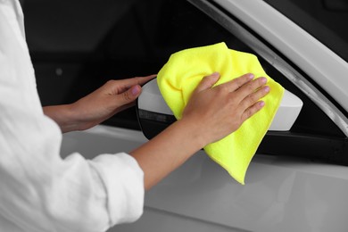 Photo of Woman cleaning car side view mirror with rag, closeup