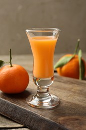 Photo of Delicious tangerine liqueur and fresh fruits on table, closeup