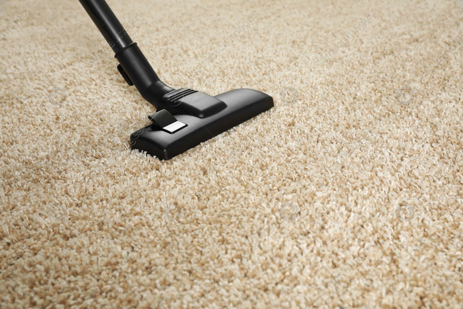 Photo of Removing dirt from beige carpet with modern vacuum cleaner. Space for text