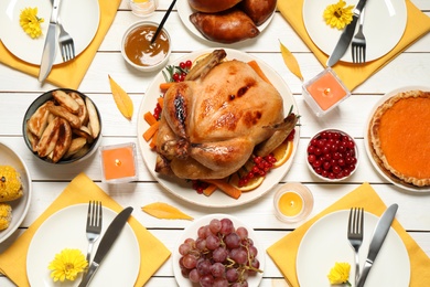 Photo of Traditional Thanksgiving day feast with delicious cooked turkey and other seasonal dishes served on white wooden table, flat lay
